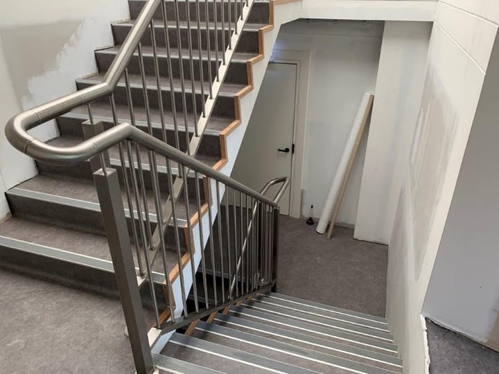 Stair with a curved metal handrail and vertical balusters following the flight