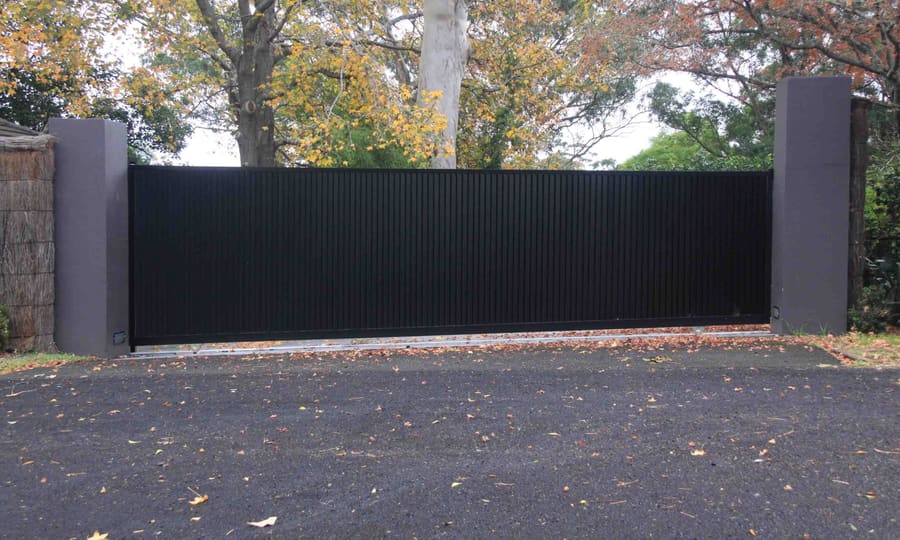 Charcoal metal driveway gate between rendered piers